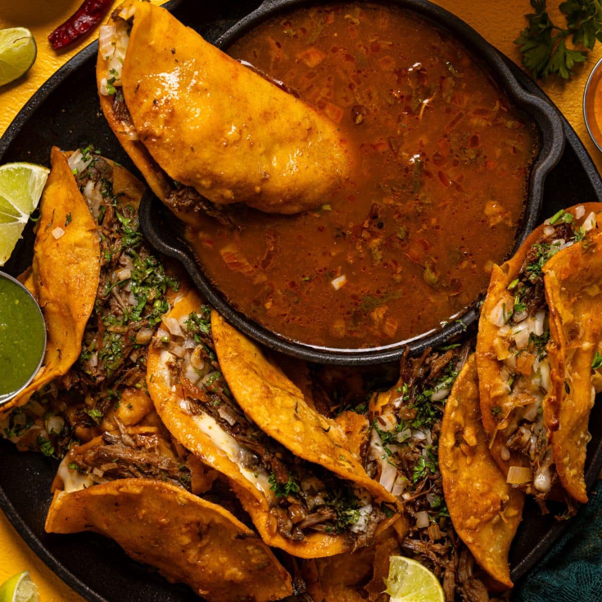 Birria street tacos griddled crisp, served with a cup of consommé